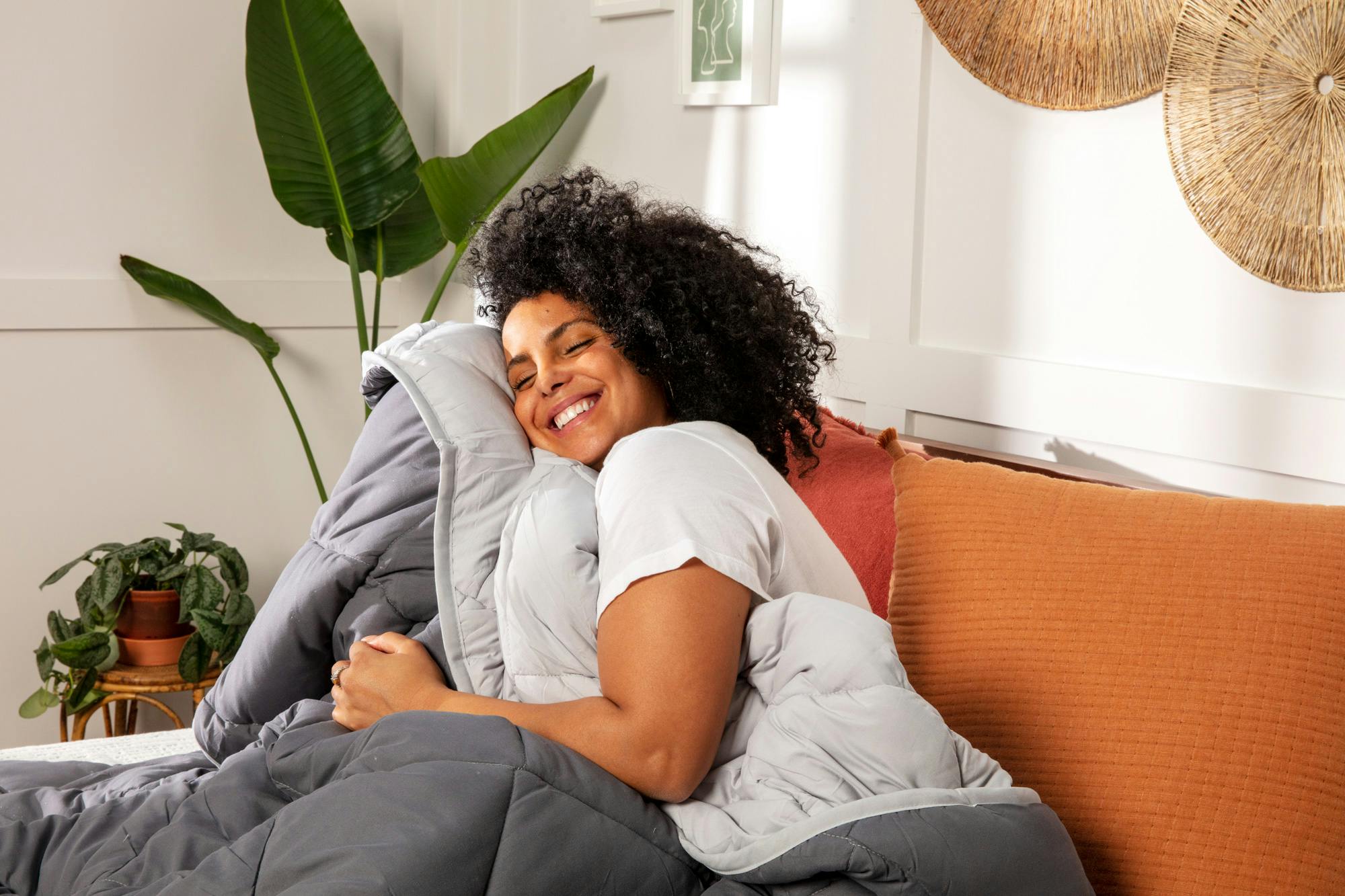 a woman smiling and pressing her face to a reversible grey comforter
