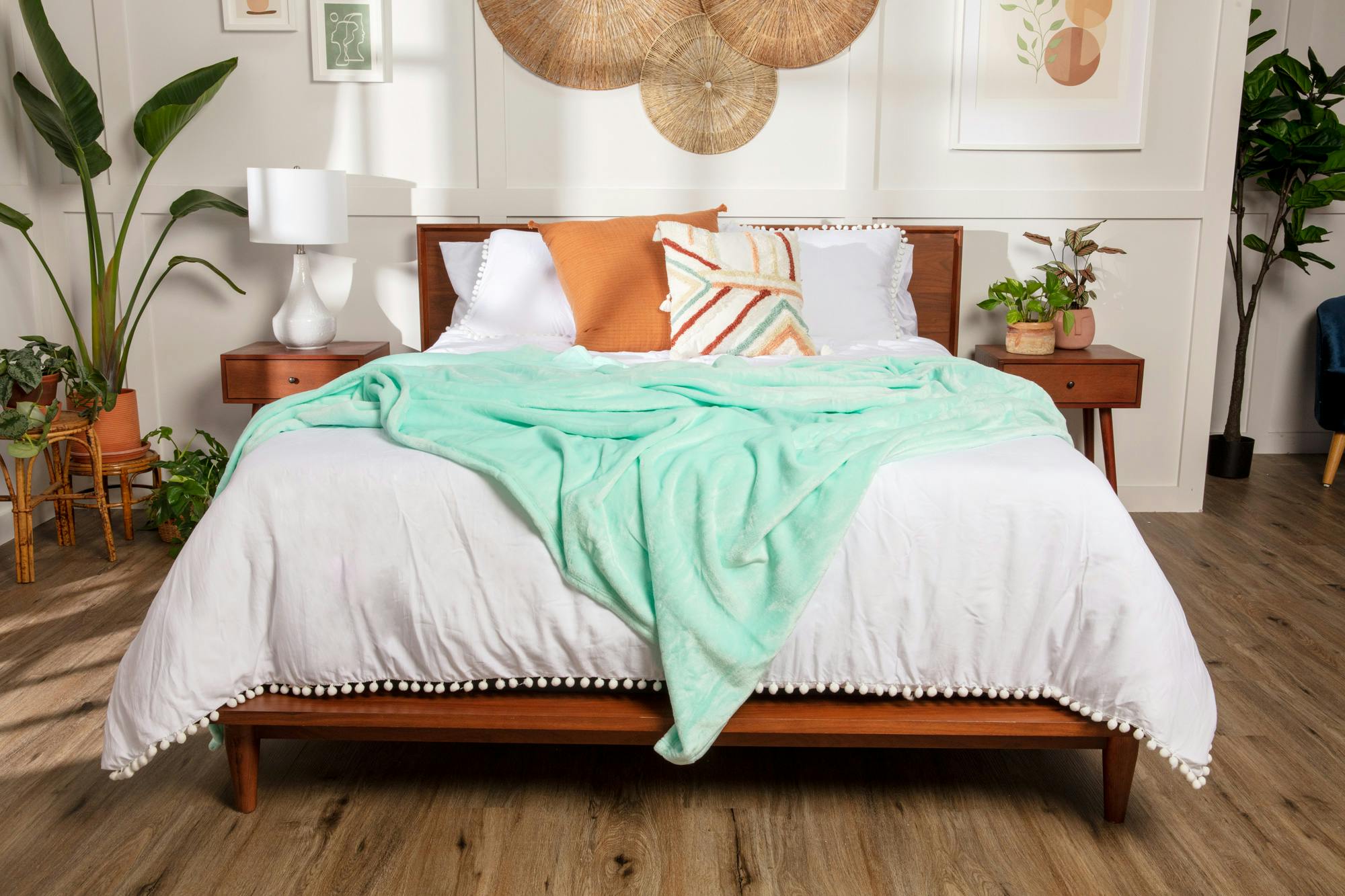 a bed with a seafoam teal fleece blanket draped across the foot of the bed
