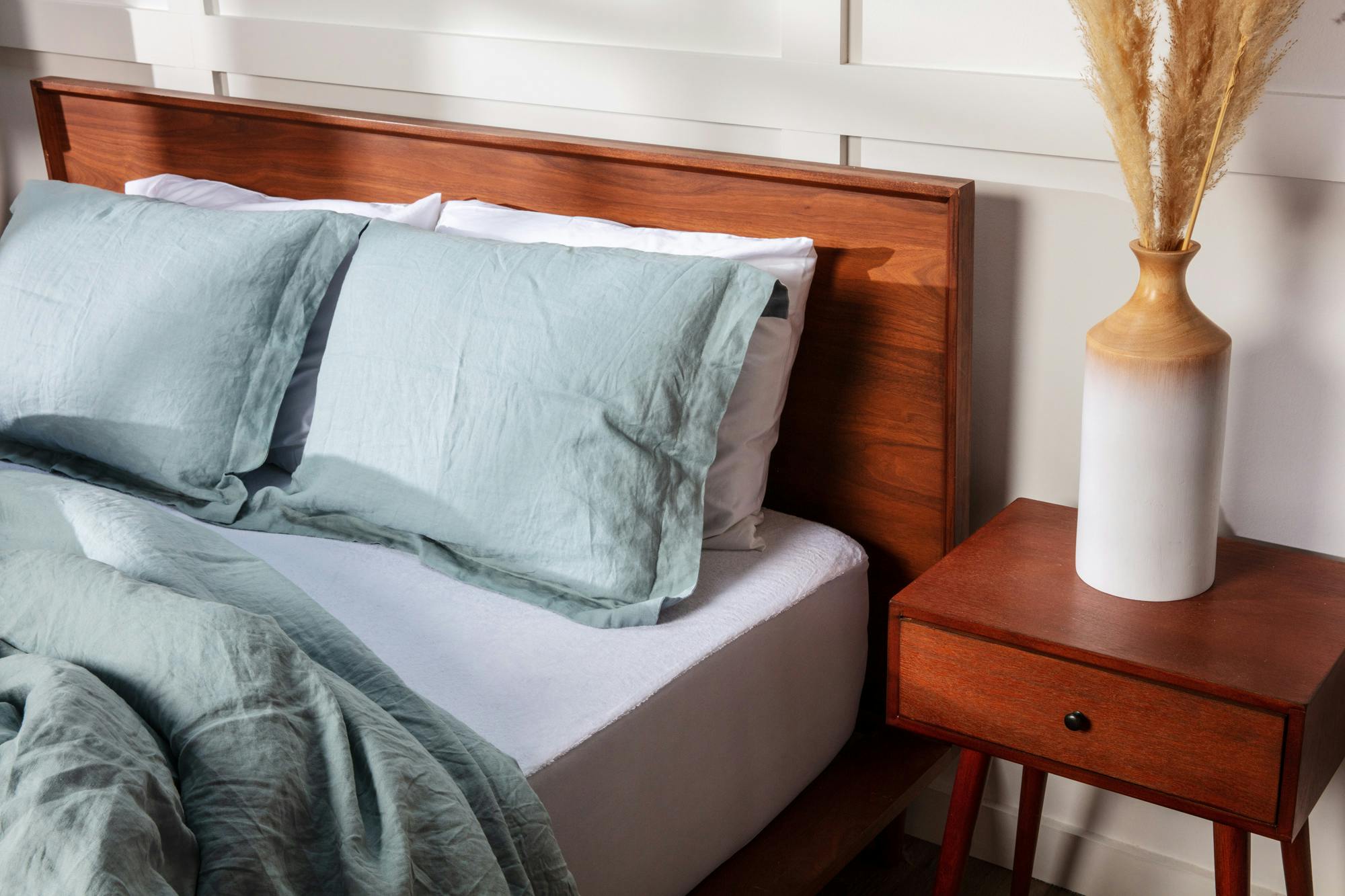 a bed with a white micro cotton mattress protector and blue bedding