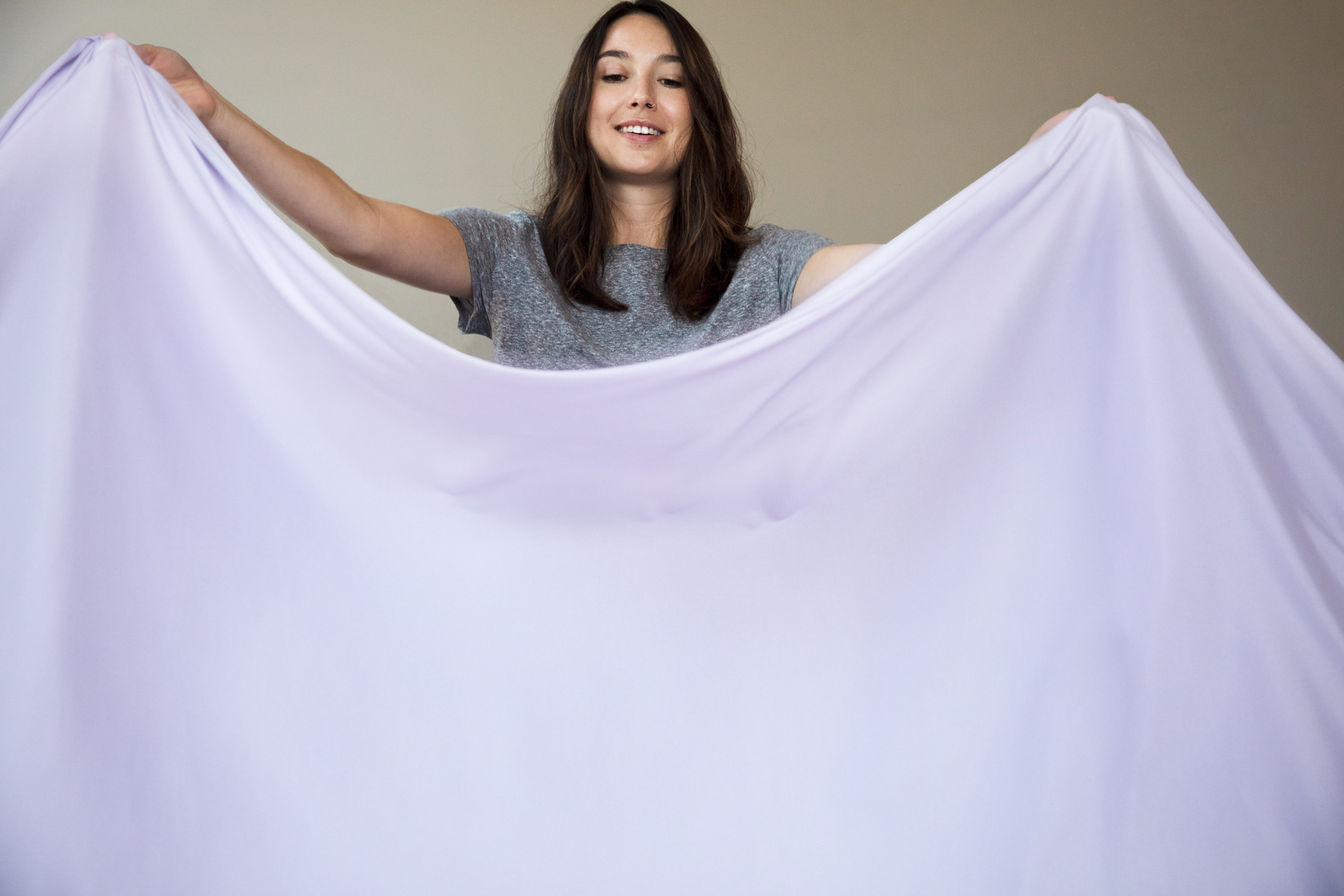 woman holding top sheet over bed
