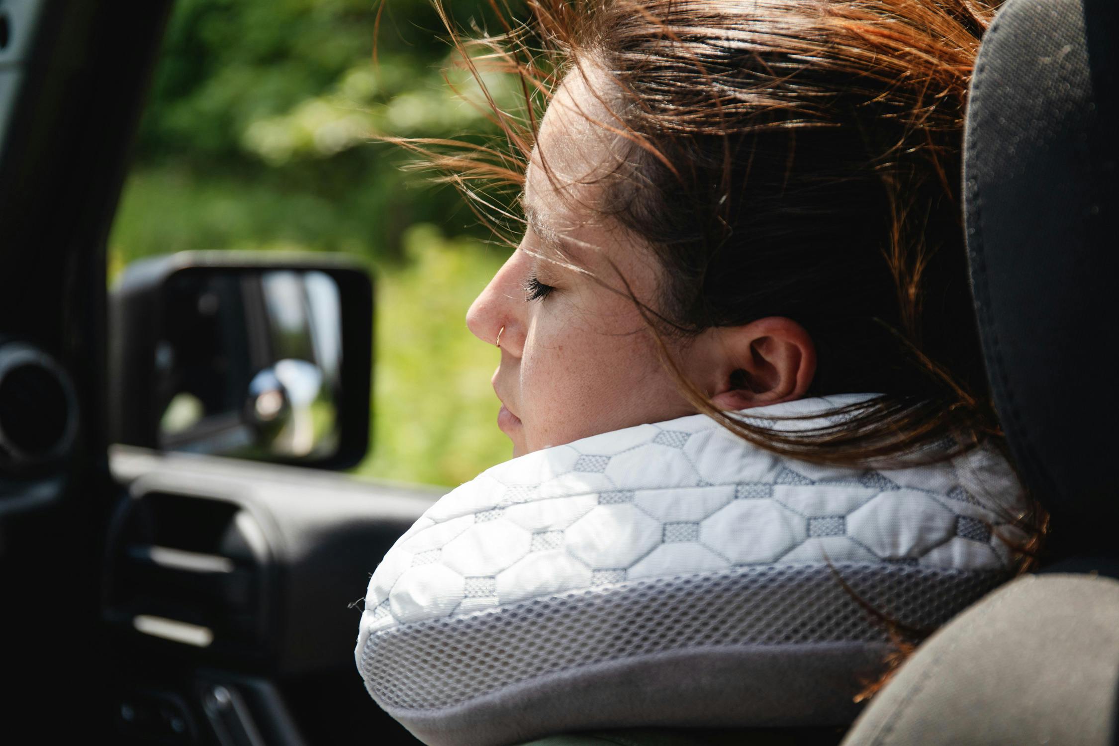 photo of a woman asleep in a car while using a viscosoft neck pillow