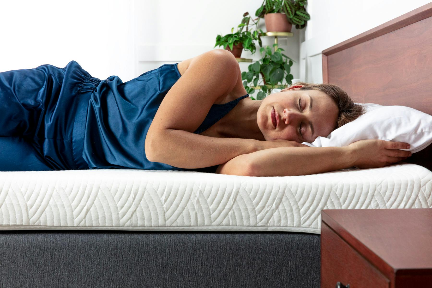 Woman sleeping on her side on a thick white mattress topper