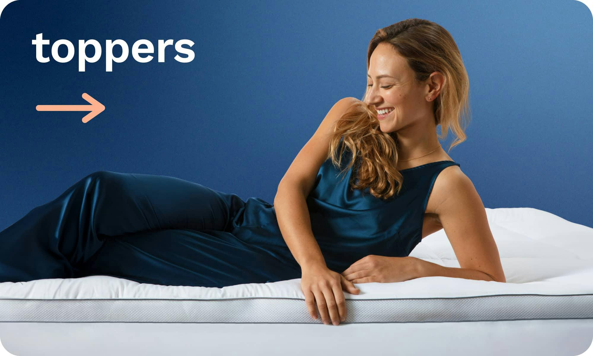 Mattress Toppers; A young woman leaning back on her elbow and smiling while resting on a white, plush, quilted mattress topper