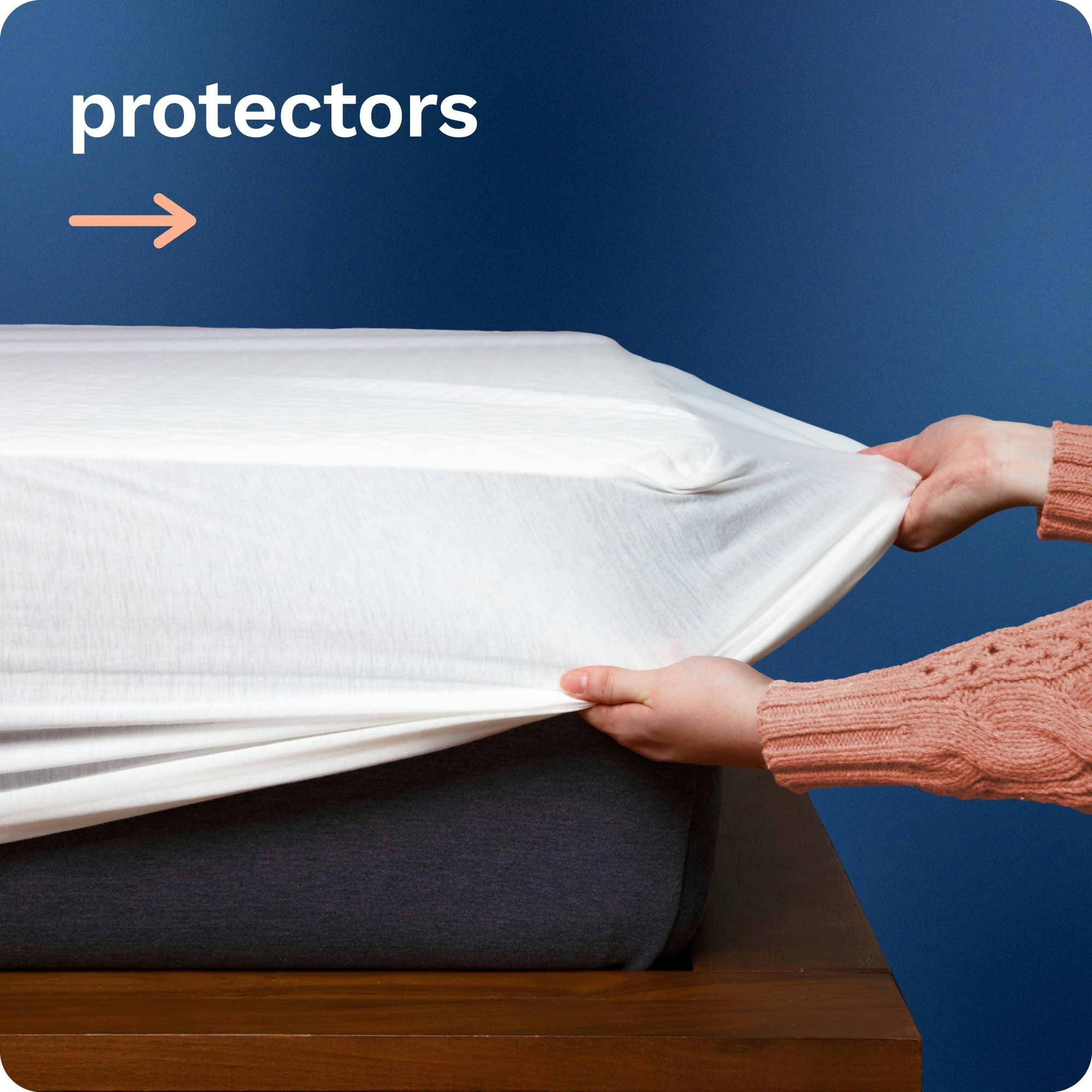 Mattress Protectors; A person pulling the elastic skirt of a white mattress protector over the corner of a mattress