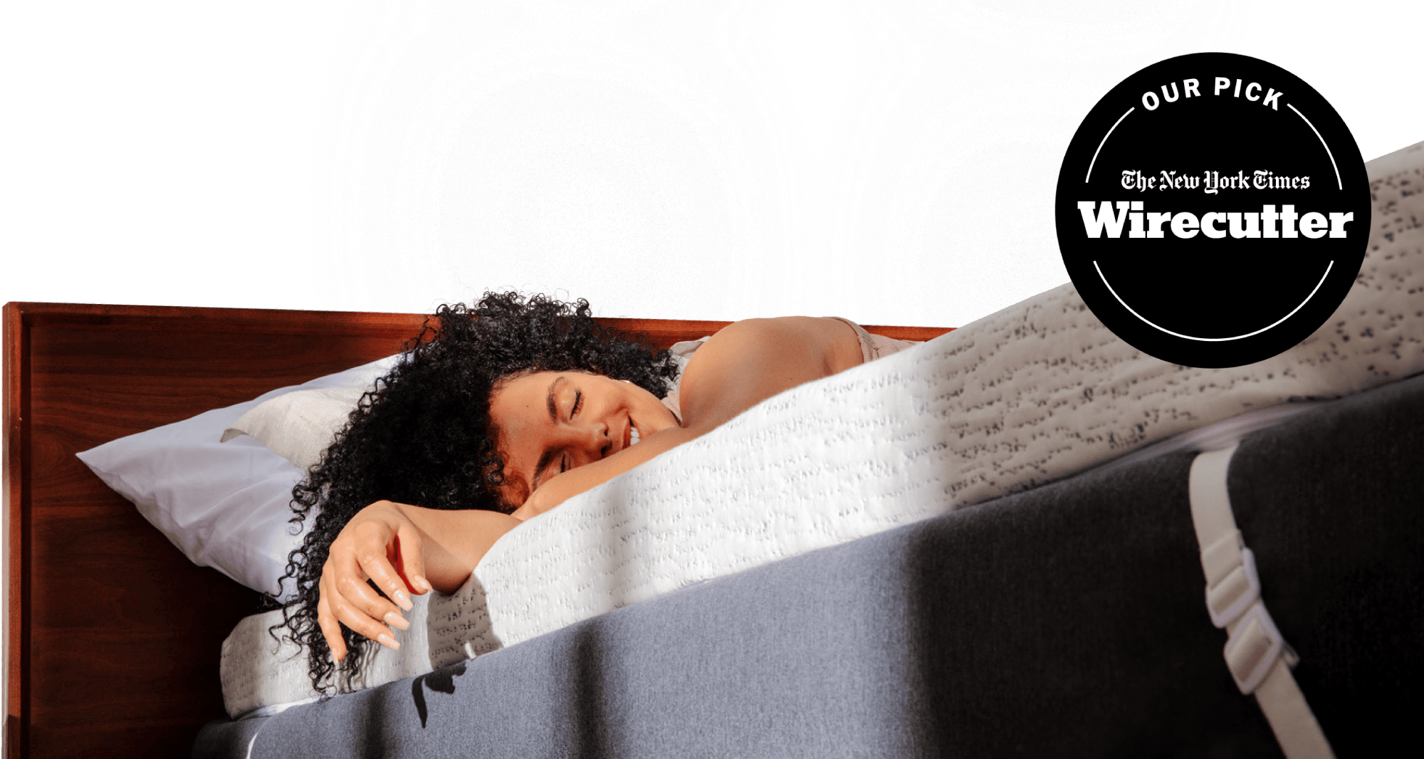 NYT Wirecutter's pick for best memory foam mattress topper; a woman relaxing on a thick white and blue mattress topper with morning light streaming on her