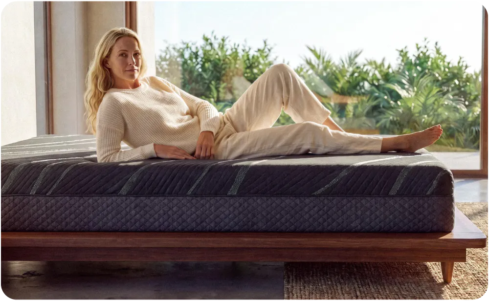 A woman lounging on the edge of a mattress, demonstrating that the mattress has superior edge support