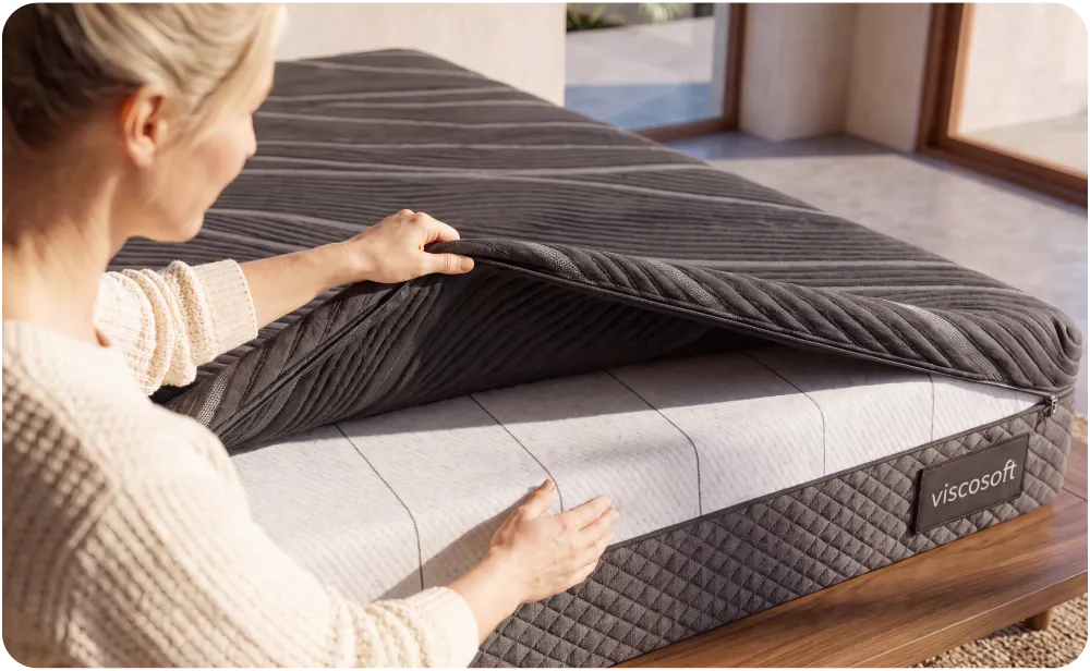 A woman unzipping a removable, machine washable mattress cover