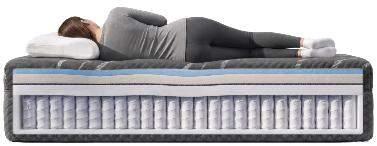 A woman sleeping on a black mattress that is showing the internal construction consisting of a medium-firm comfort layer with a hybrid foundation