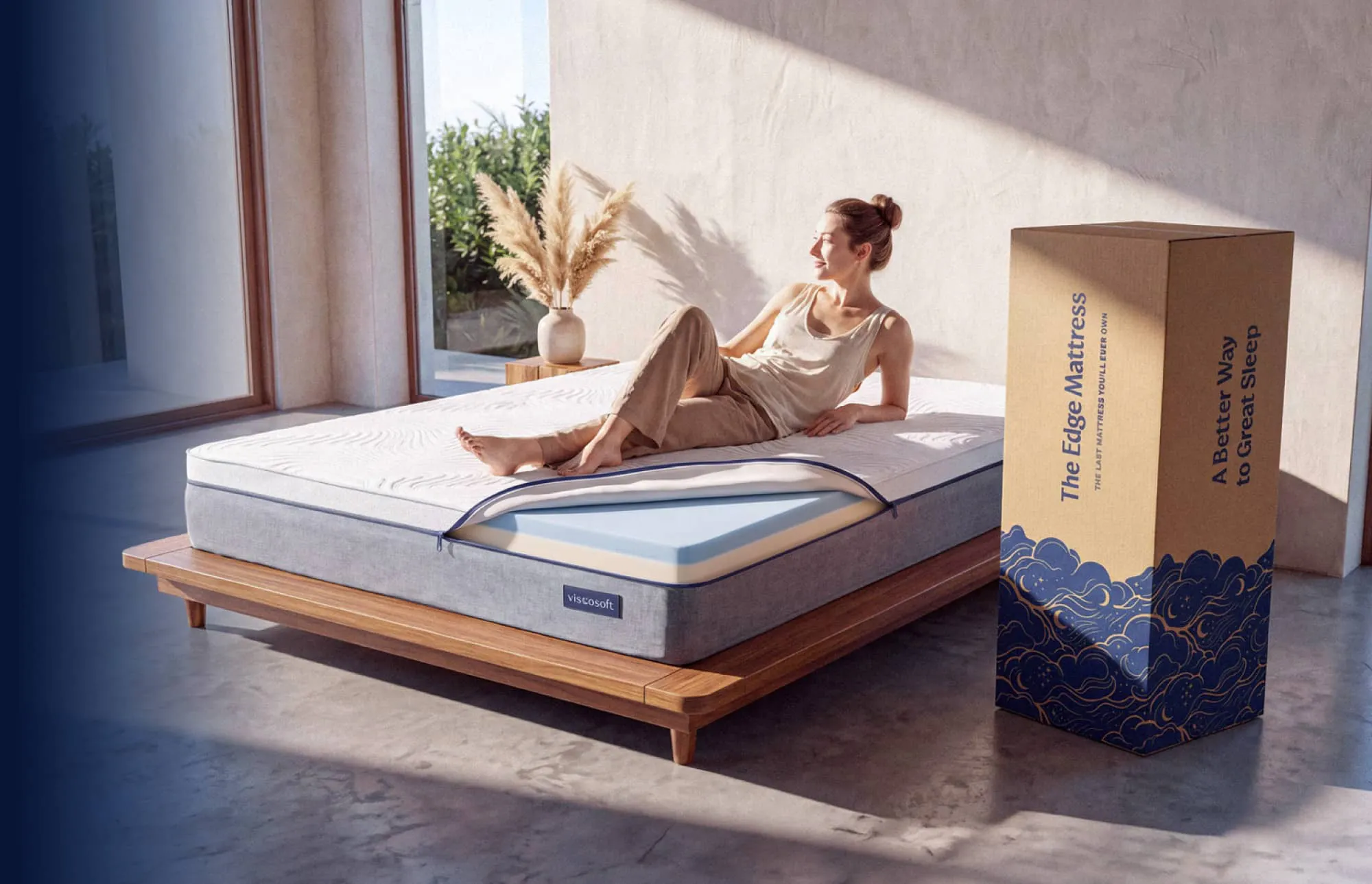 A woman lounging on a white and gray mattress with the corner unzipped and showing a dual memory foam comfort layer.