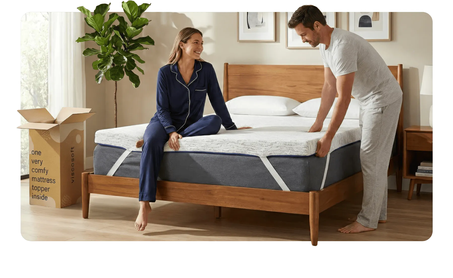 A man and woman unbox their new thick white mattress topper and secure it to a gray mattress with white elastic adjustable straps