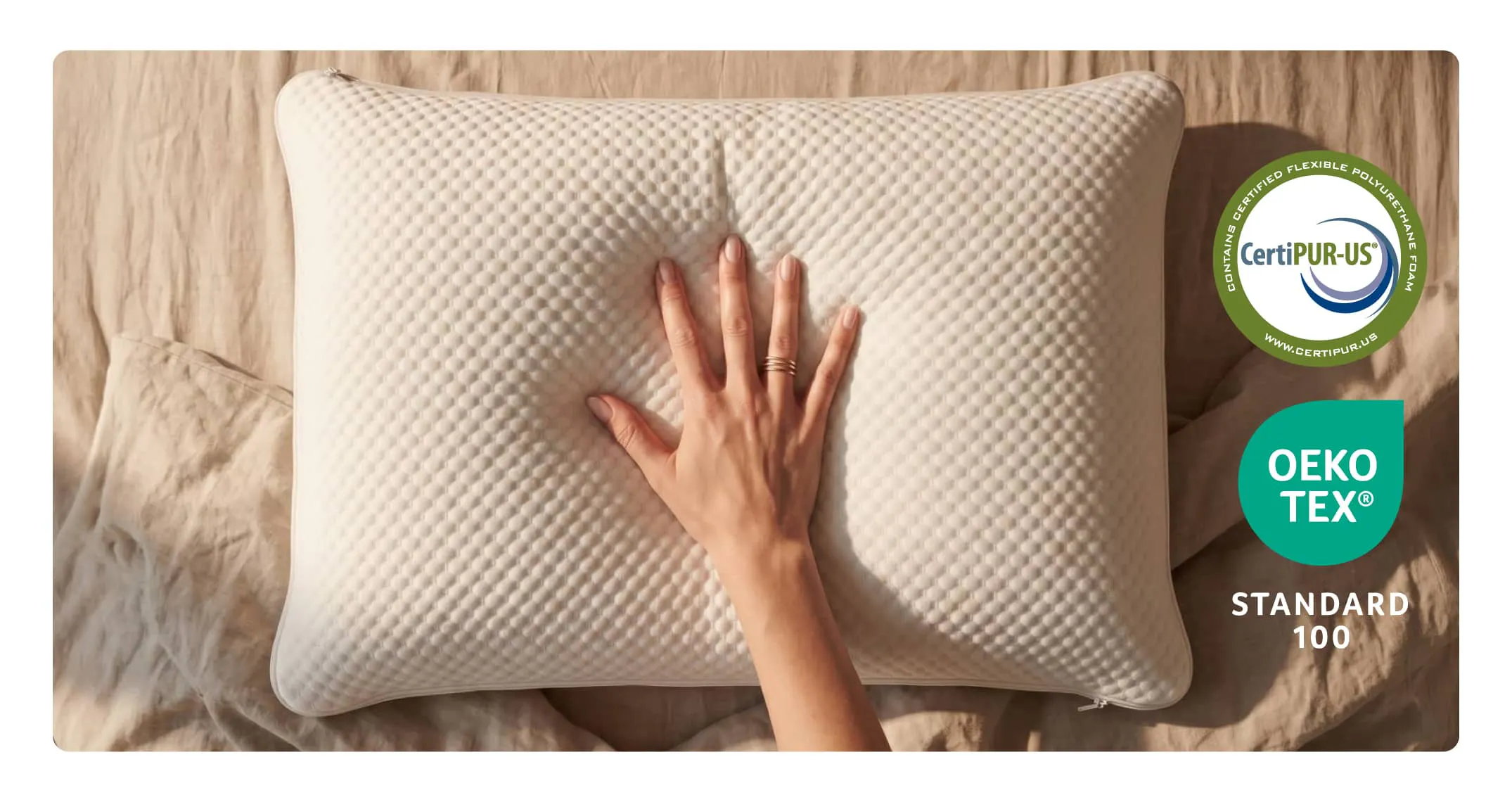 A hand pressing into a pillow to show the responsive nature of the memory foam. CertiPUR-US and OEKO TEX Standard 100 badges.