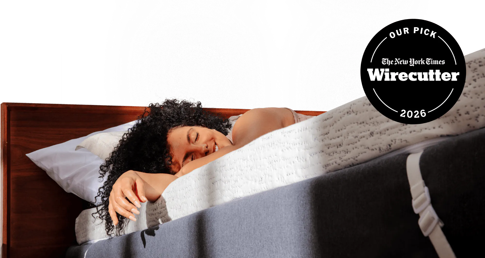 NYT Wirecutter's pick for best memory foam mattress topper; a woman relaxing on a thick white and blue mattress topper with morning light streaming on her